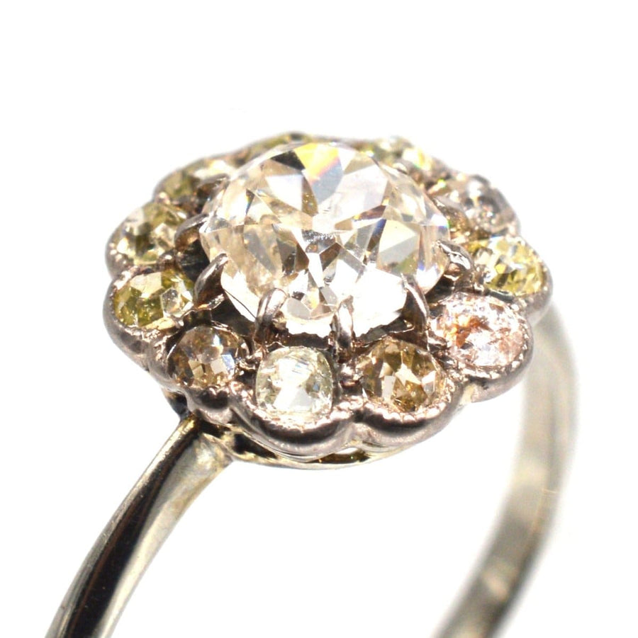 Edwardian 18ct white gold ring featuring an old mine cut diamond surrounded by tinted cluster diamonds.