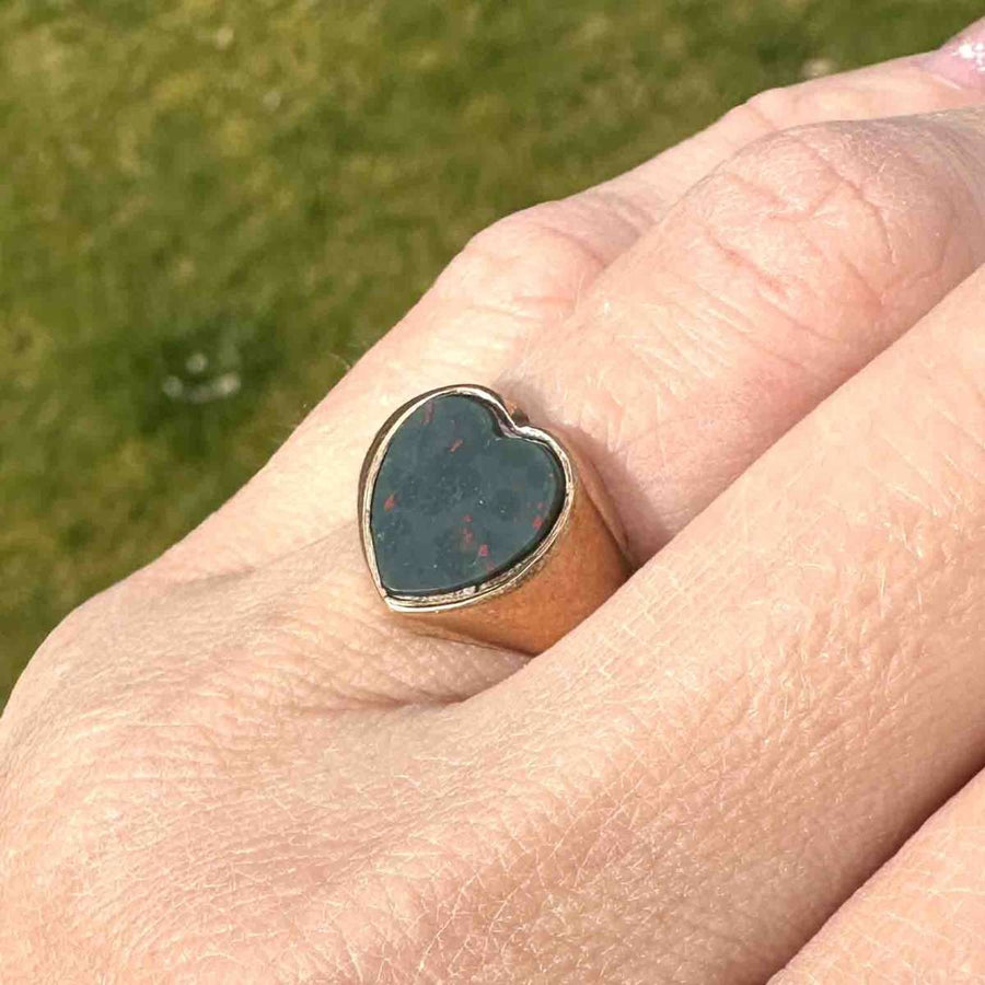 Edwardian 9ct gold heart-shaped bloodstone signet ring on a hand, showcasing its unique craftsmanship and romantic design.