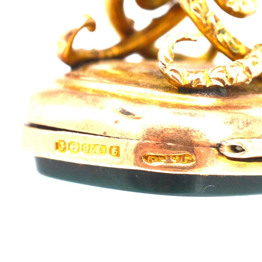 Close-up of Edwardian 9ct gold locket seal pendant with embossed swirl knot design and bloodstone base.