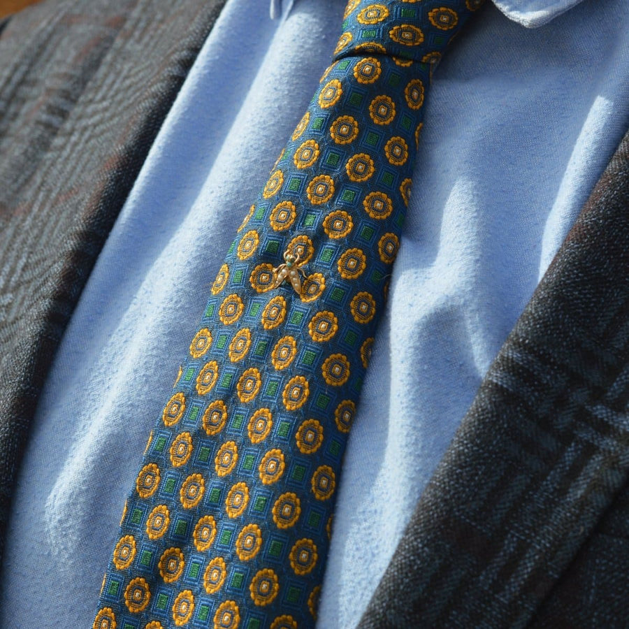 Edwardian bug tie pin featuring turquoise stones and seed pearls on a patterned silk tie.