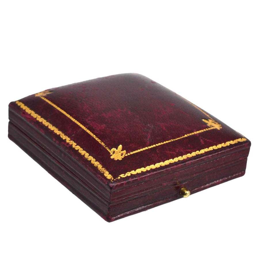 Antique burgundy leather box with golden decorative accents and a keyhole, perfect for jewelry storage.
