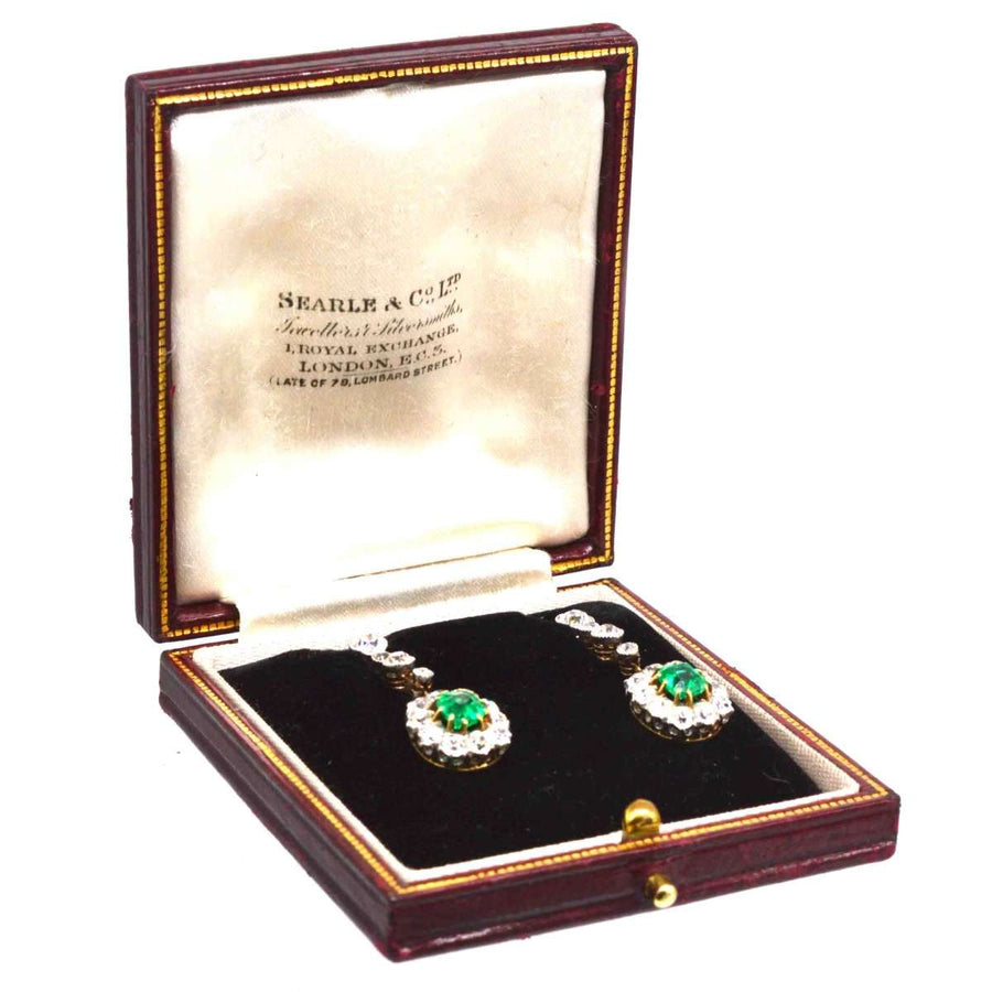 Edwardian emerald and diamond drop earrings in burgundy box, showcasing vibrant Colombian emeralds and sparkling diamonds.