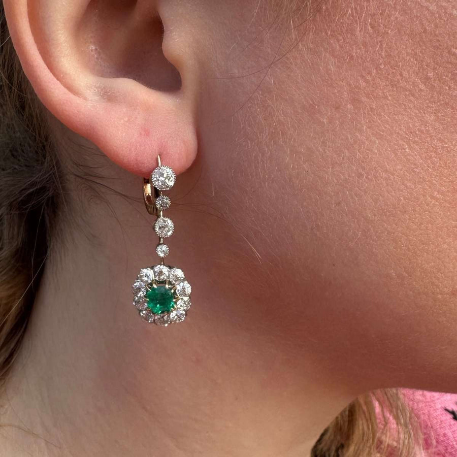 Edwardian emerald and diamond cluster drop earrings showcased on earlobe, highlighting vibrant Colombian emerald and elegant diamonds.
