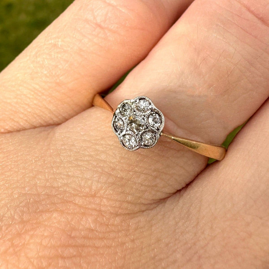 Edwardian diamond daisy cluster ring on a hand, featuring a millegrain setting and delicate floral design.
