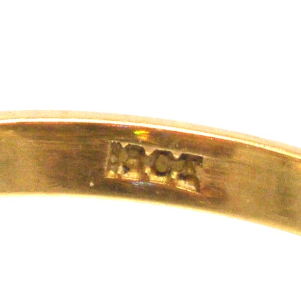 Close-up of the inside of an Edwardian diamond daisy cluster ring, showing the hallmark and detailed craftsmanship.