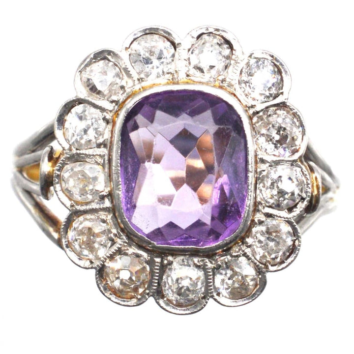 Edwardian platinum and gold amethyst diamond cluster ring with triple loop shoulders, featuring a stunning amethyst center.