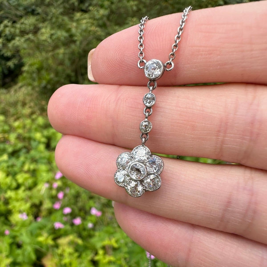Edwardian platinum diamond cluster drop necklace featuring a floral design and suspended diamonds, elegant jewelry.