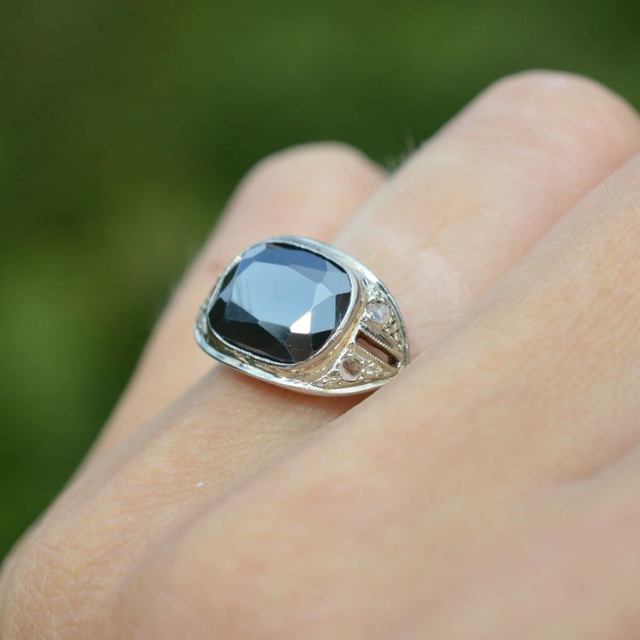 French Art Deco 18ct gold and platinum hematite and diamond ring on a finger in natural light.