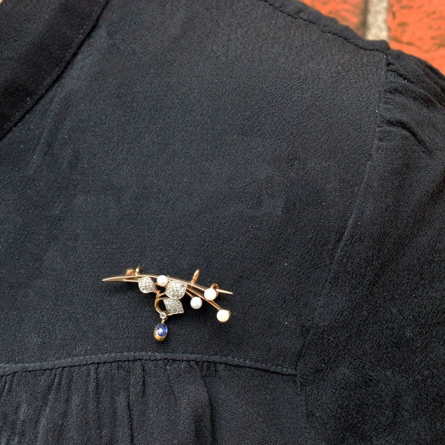 French Art Nouveau 14ct gold brooch with diamonds, pearls, and cabochon sapphire worn on a black shirt.