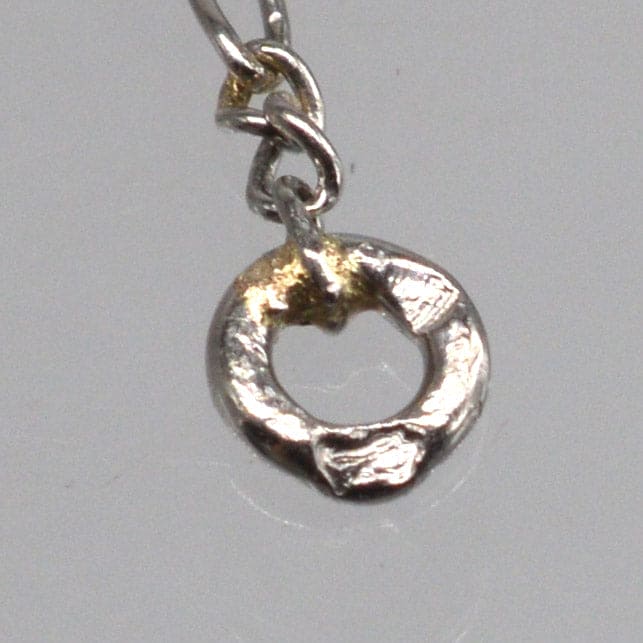 Close-up of a silver and gold pendant on a chain, showcasing its unique circular design.