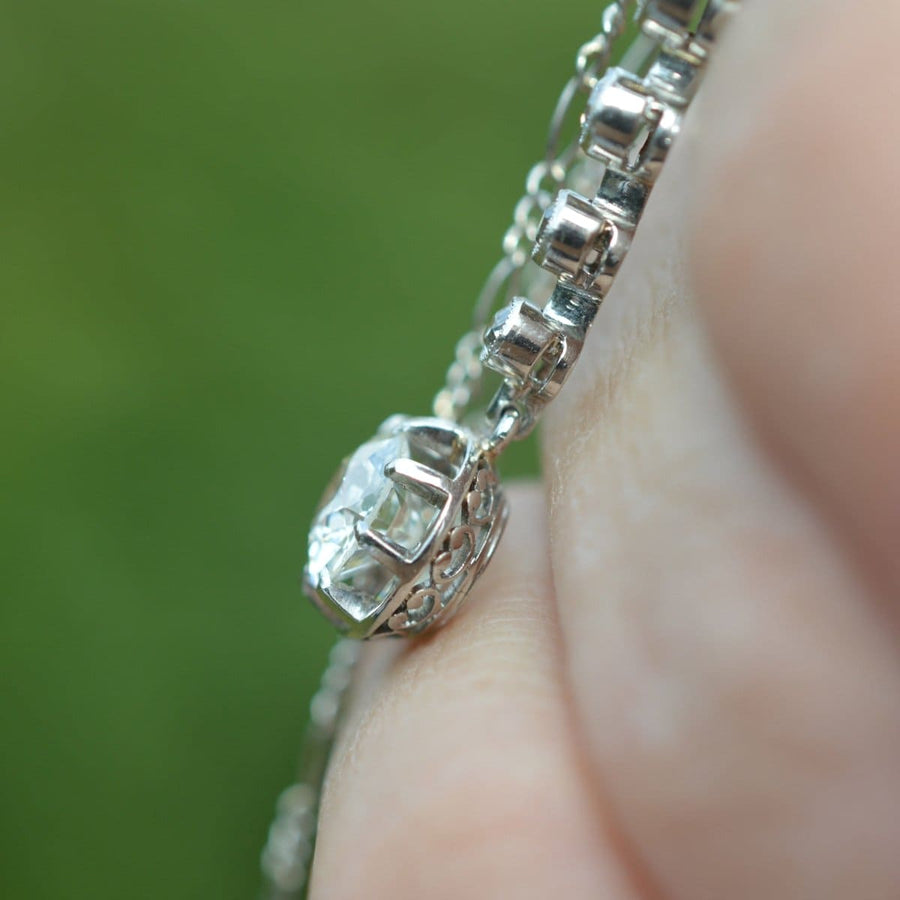Close-up of a diamond drop pendant necklace showcasing intricate claw setting in platinum and white gold.