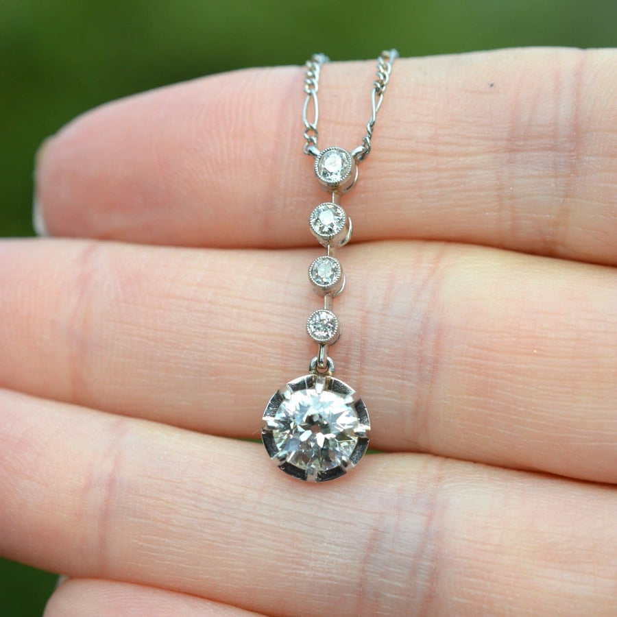 Belle Epoque diamond drop pendant necklace with a large clear diamond and three smaller diamonds, held in a hand.