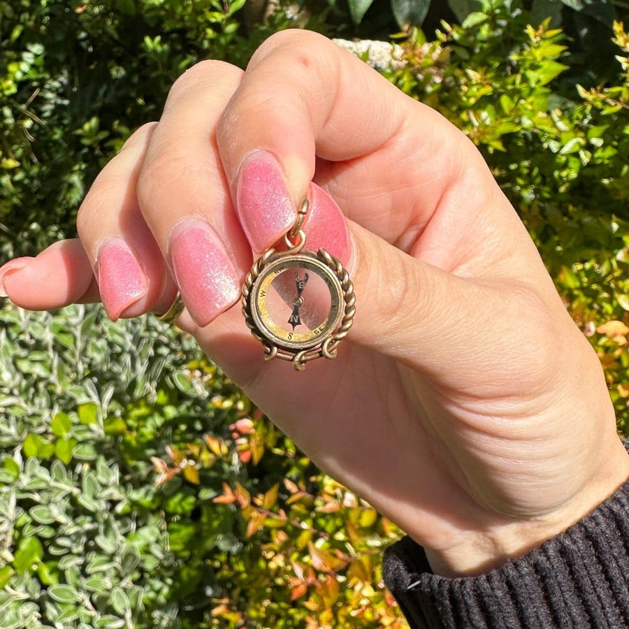 Late Victorian 9ct gold compass pendant charm held in hand, showcasing its nautical design and spinning needle.