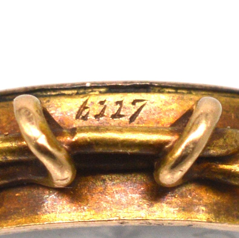 Close-up of the engraved serial number 6117 on a vintage gold pendant charm.