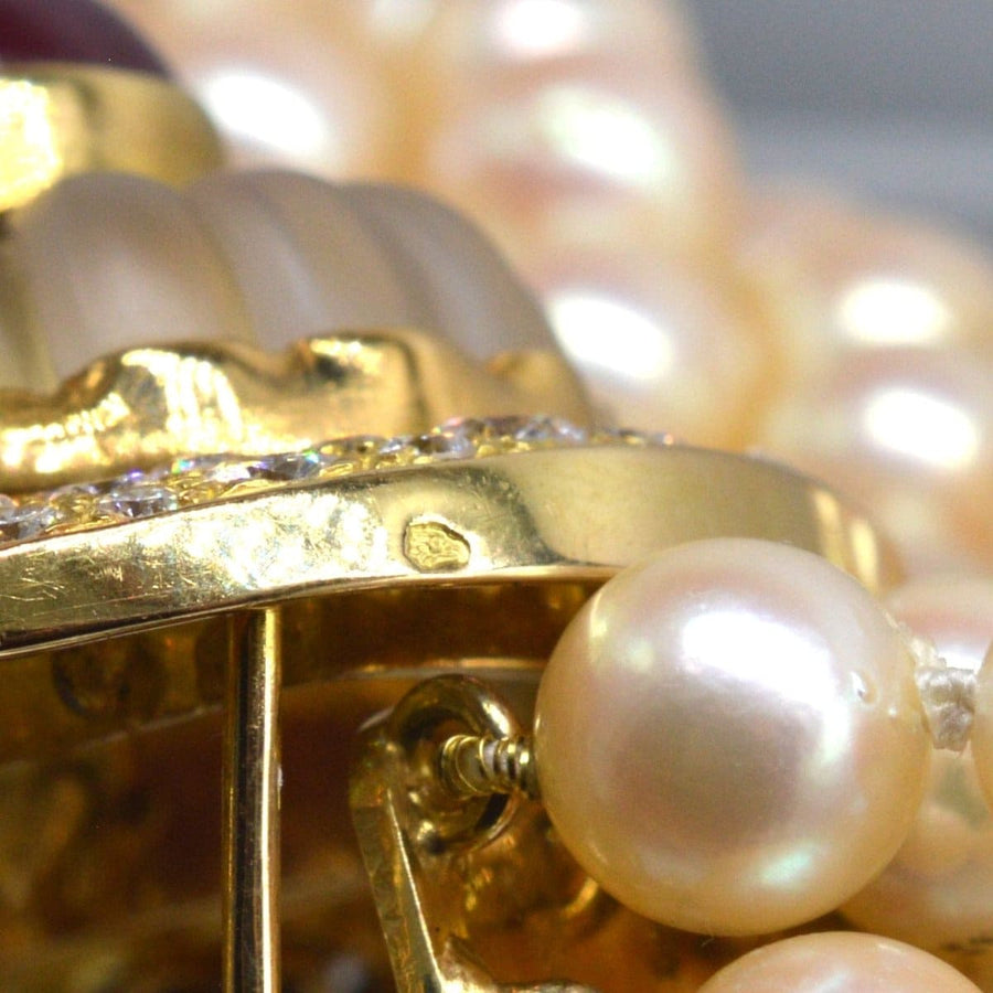 Close-up of a gold clasp featuring ruby, diamond, and rock crystal on a cultured pearl necklace.