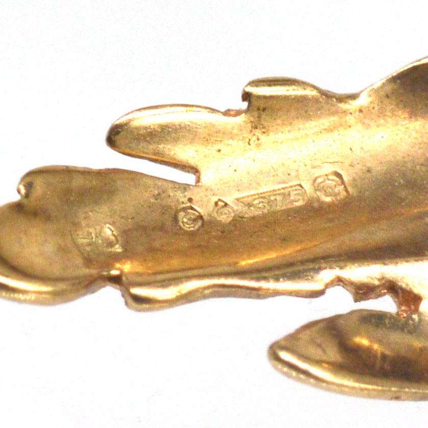Close-up of a mid-century modernist gold spray brooch featuring intricate floral design and hallmark details.