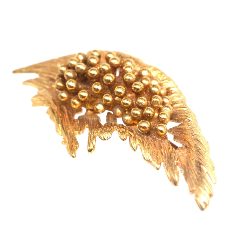Mid-century modernist gold spray brooch featuring a floral design with bold gold beads, ideal for dresses or jackets.