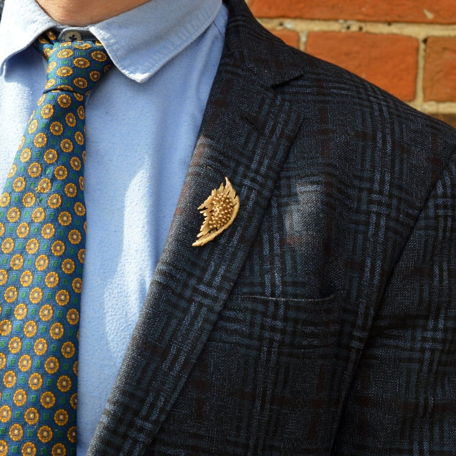 Mid-century modernist gold spray brooch worn on a suit lapel, showcasing its floral, bold design.