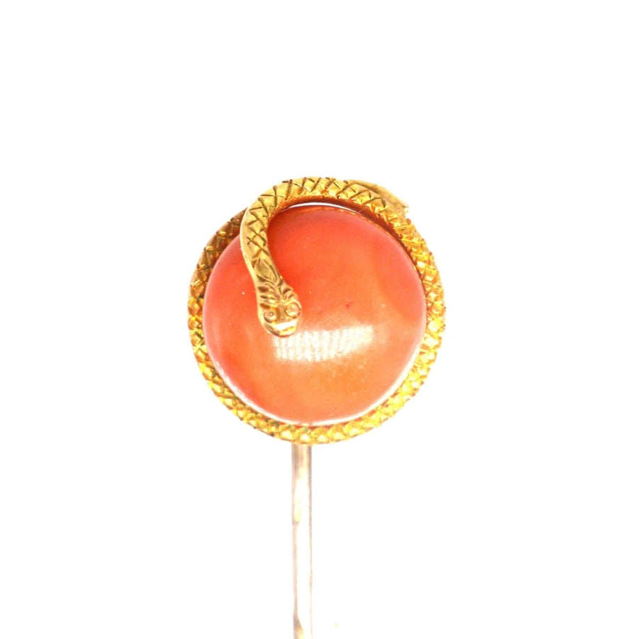Gold snake brooch with carnelian stone, symbolizing rebirth and transformation in vintage jewelry design.