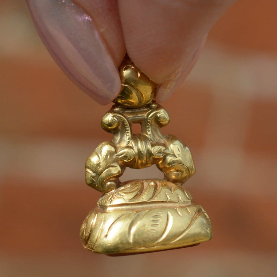 Regency gold cased seal featuring intricate design, held delicately, showcasing craftsmanship and elegance.