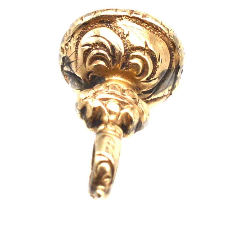 Regency gold cased small seal charm featuring intricate repousse work and a chalcedony stone base.
