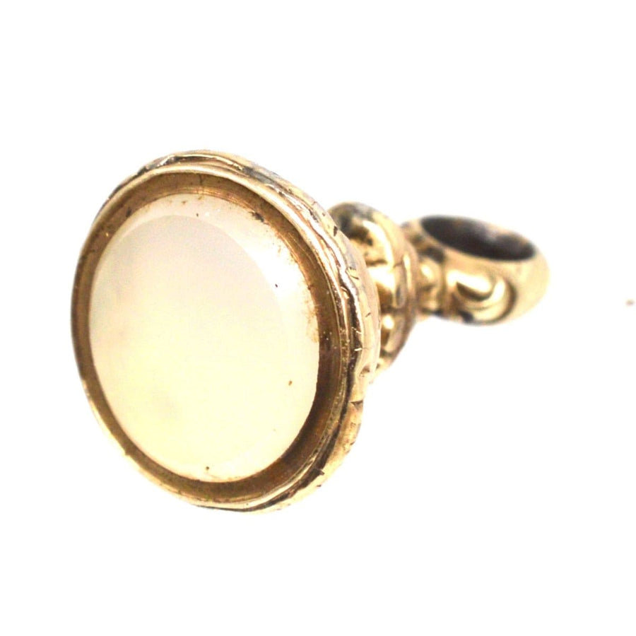 Regency gold cased small seal charm featuring a chalcedony base and intricate repousse detail.