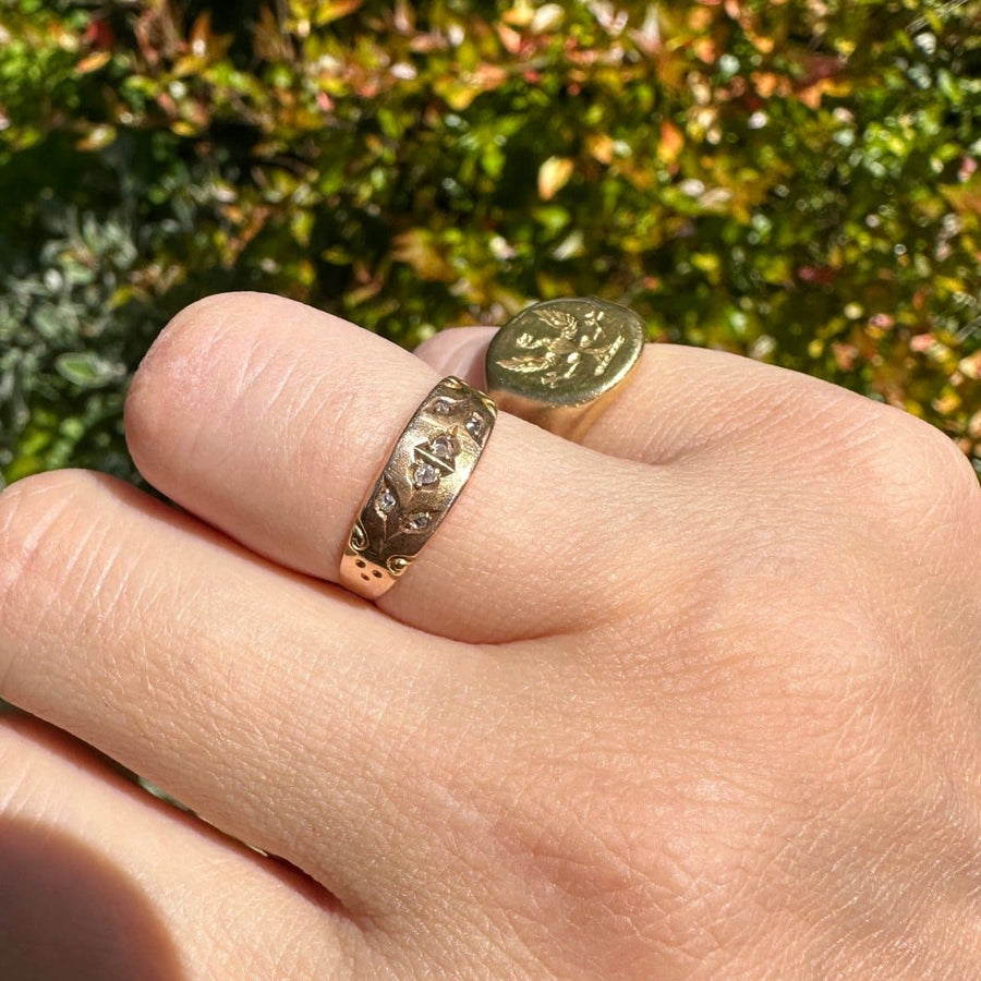 Victorian 15ct gold band ring with rose cut diamonds worn on a hand, showcasing its intricate design.
