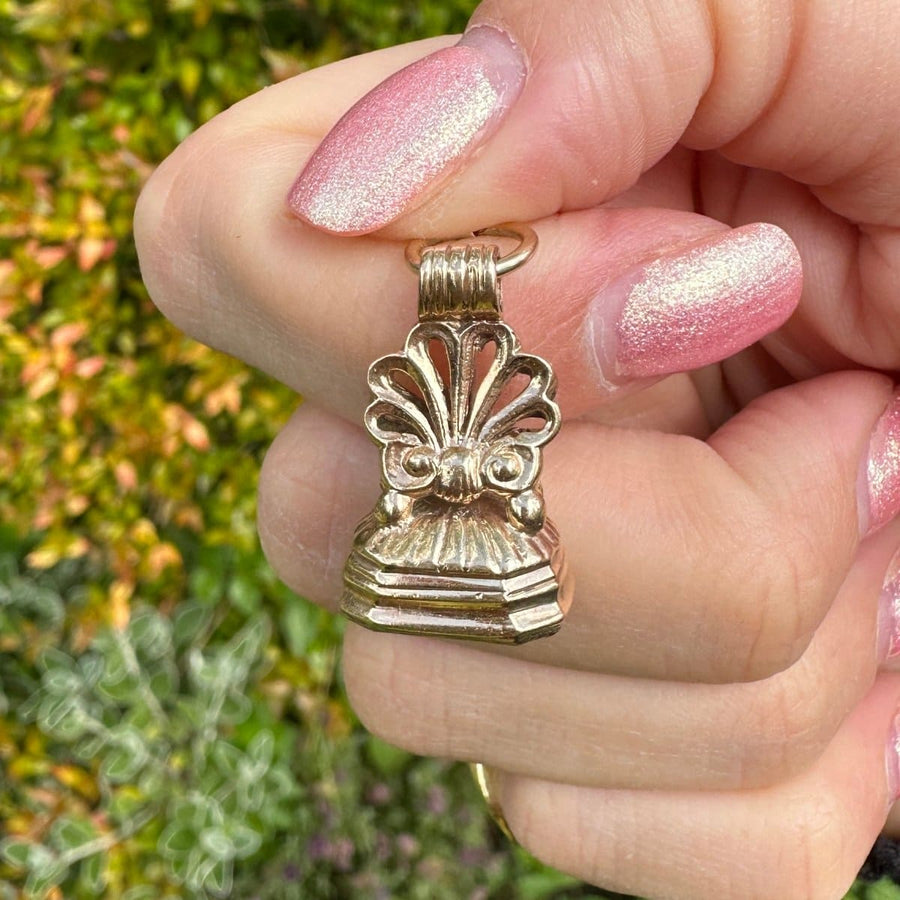 Victorian 9ct gold scallop shell seal pendant held in hand, featuring a bloodstone base for protection and bravery.