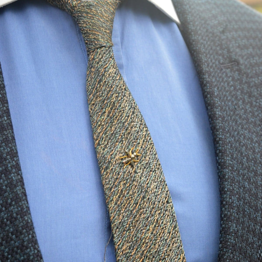 Victorian cut steel insect tie pin on a textured tie, reflecting light and adding charm to formal attire.
