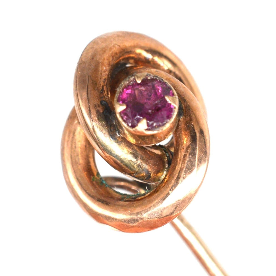 Victorian gold knot tie pin with garnet, crafted circa 1880s, symbolizing love with a grand appearance.