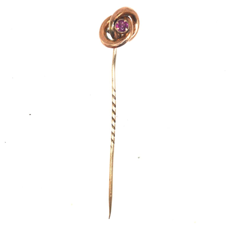 Victorian gold knot tie pin with garnet, circa 1880s, symbolizing the lover's knot, elegant accessory for formal wear.