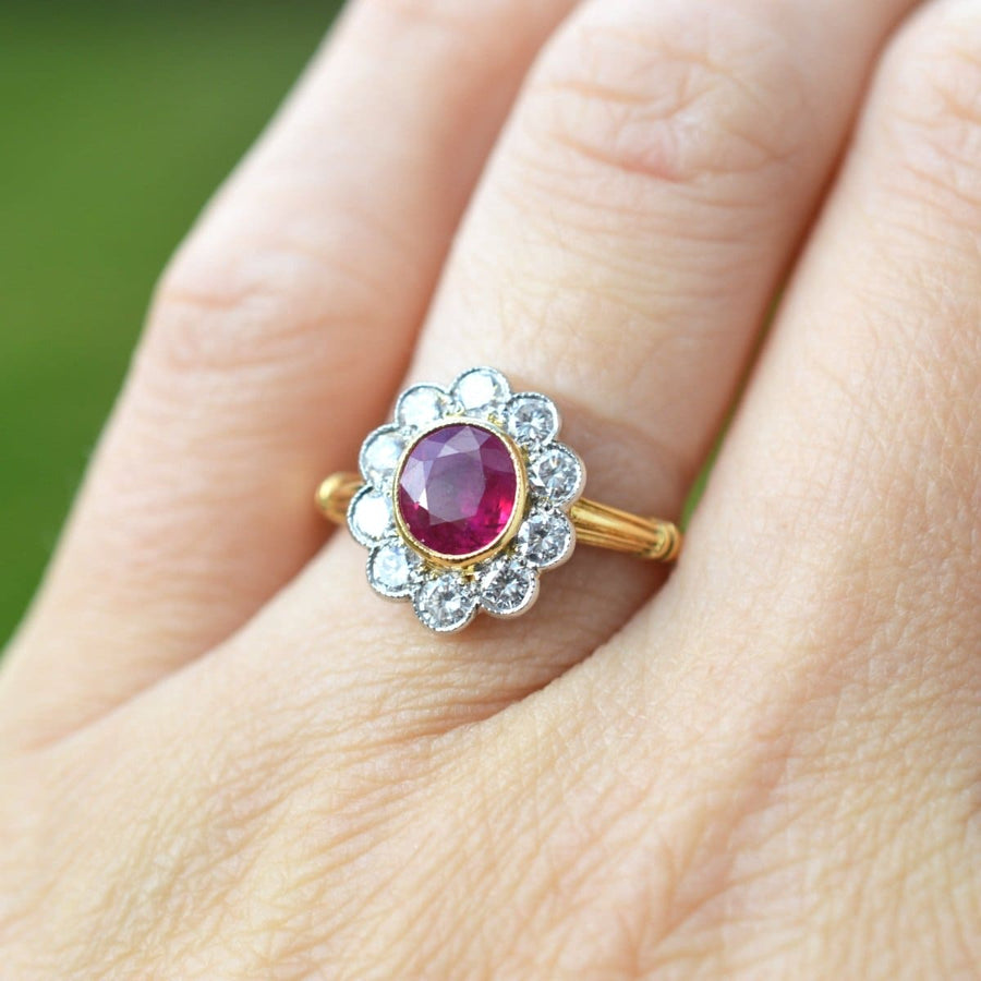 Vintage 18ct gold Burma ruby and diamond cluster ring on hand, featuring a natural ruby surrounded by ten diamonds.