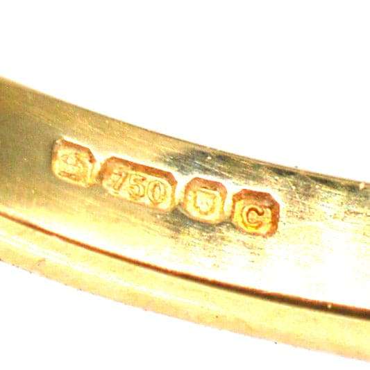 Close-up of 18ct gold hallmark and purity stamp on a vintage ring, indicating a quality of 750 gold.