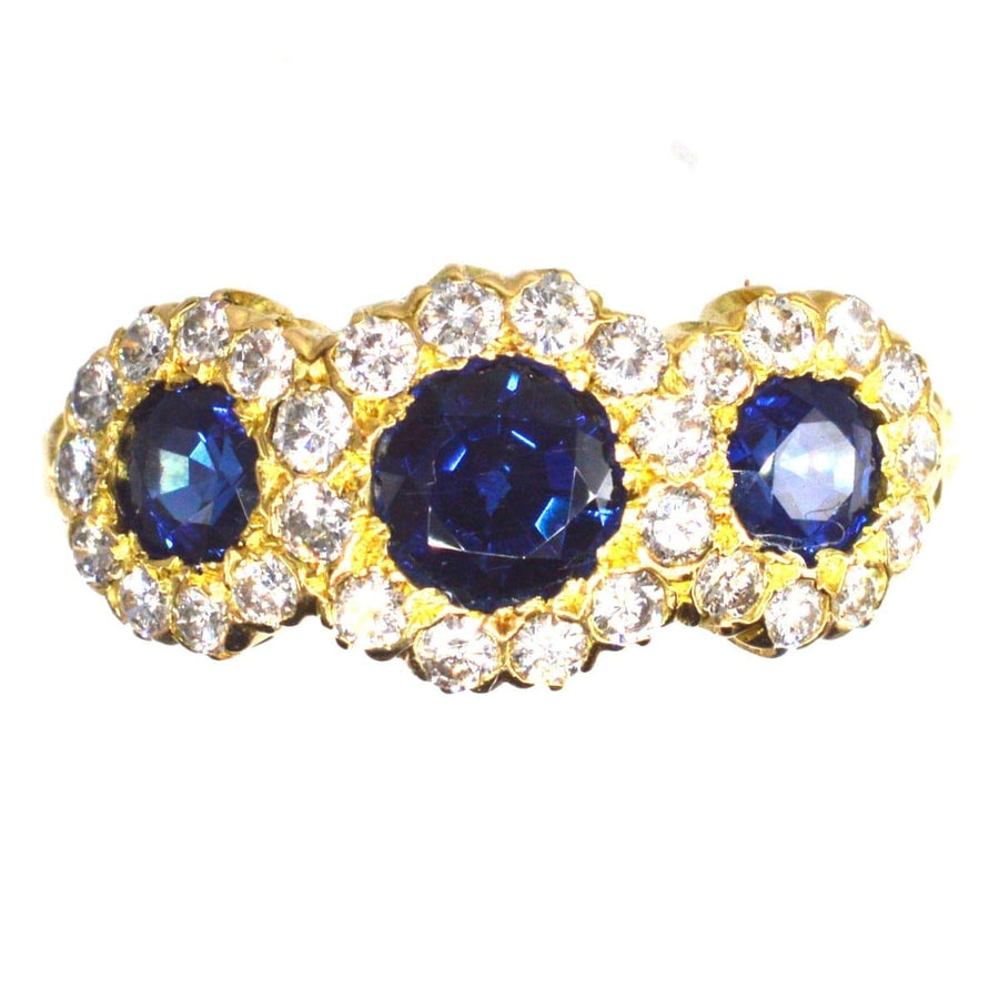 Vintage 18ct gold ring featuring three vibrant sapphires surrounded by diamond clusters, perfect for engagements or anniversaries.