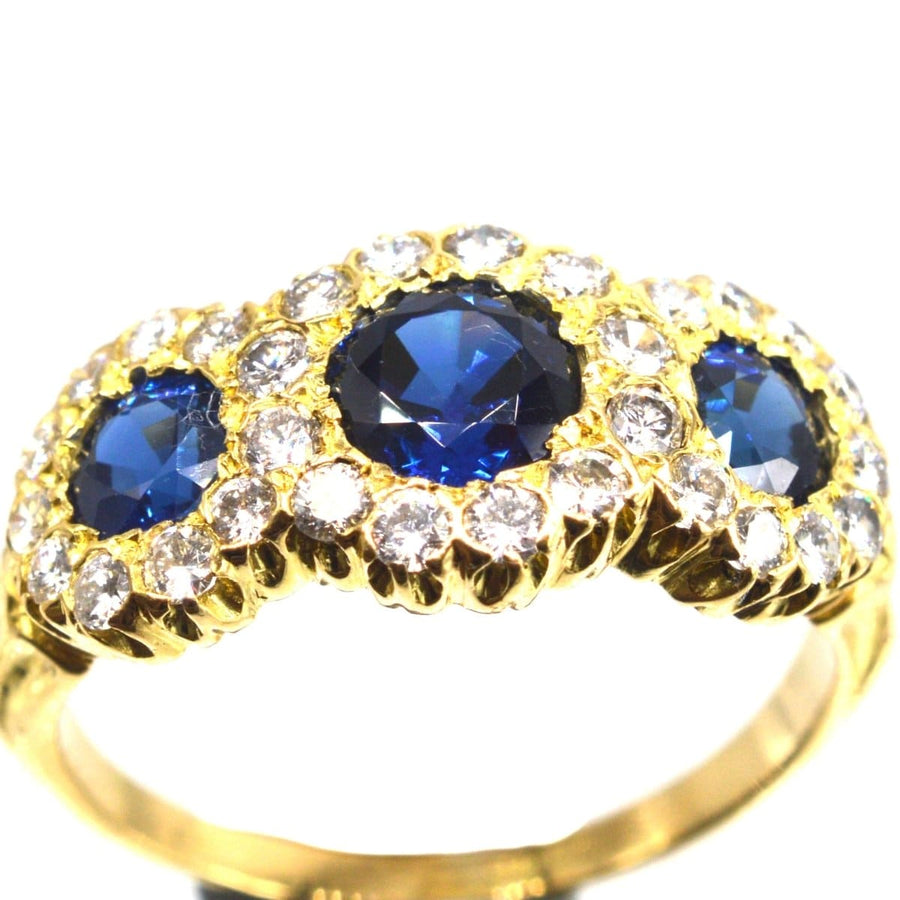 Vintage 18ct gold sapphire and diamond triple cluster ring from 1975, featuring vibrant sapphires surrounded by diamond clusters.