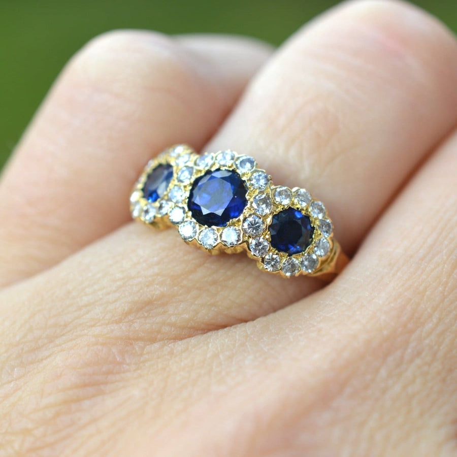Vintage 18ct gold sapphire and diamond triple cluster ring worn on a hand, showcasing vibrant sapphires and elegant diamond clusters.