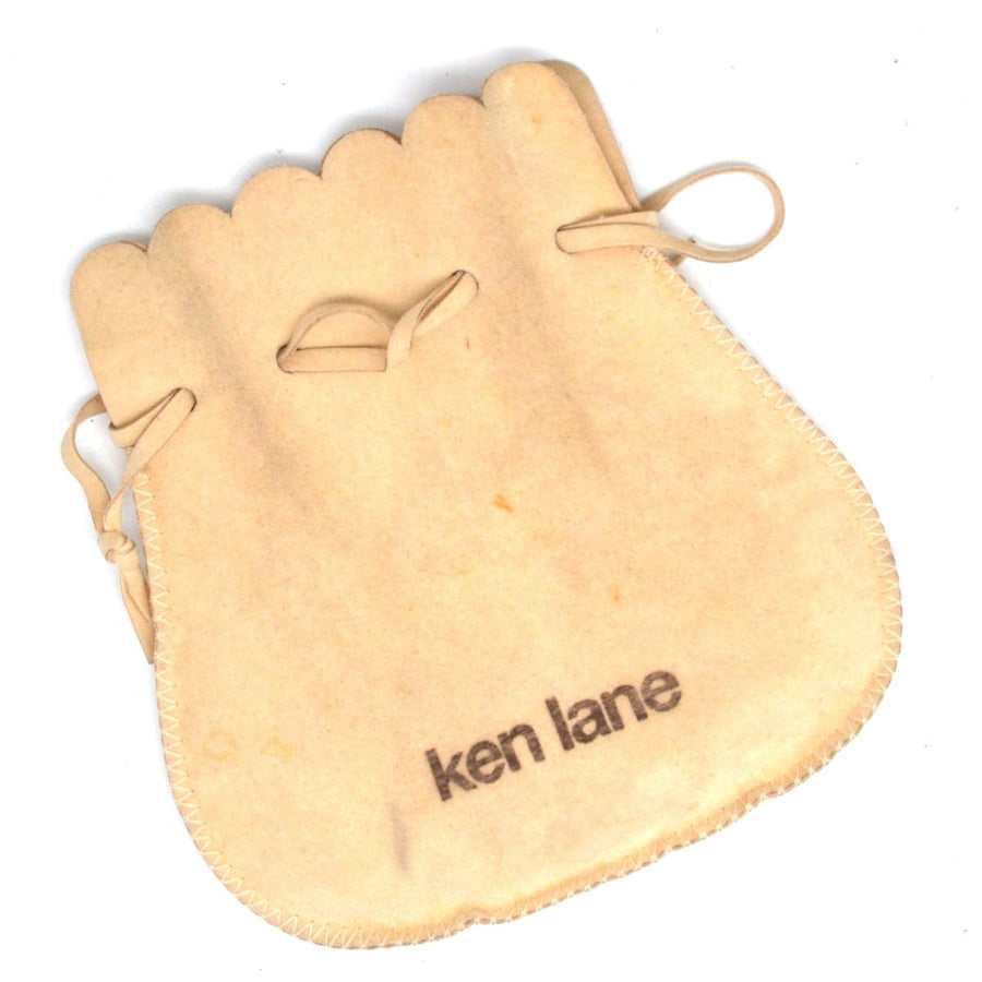 Vintage Ken Lane jewelry pouch in beige with tied closure, perfect for storing elegant earrings.