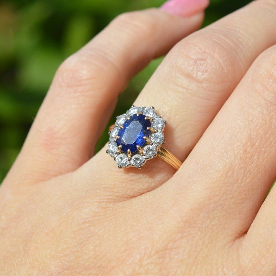 Vintage French 1960s 18ct gold sapphire and diamond cluster ring worn on a hand with a vibrant blue sapphire.