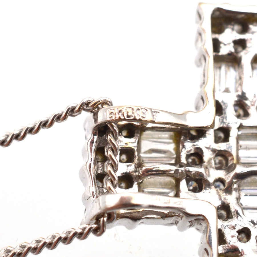 Close-up of vintage 1990s 18ct white gold cross pendant with baguette and round diamond accents.