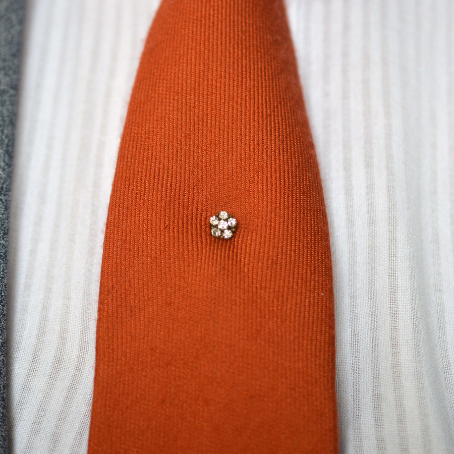 Art Deco gilt metal paste cluster tie pin on a vibrant orange silk tie, adding elegance and style to formal attire.