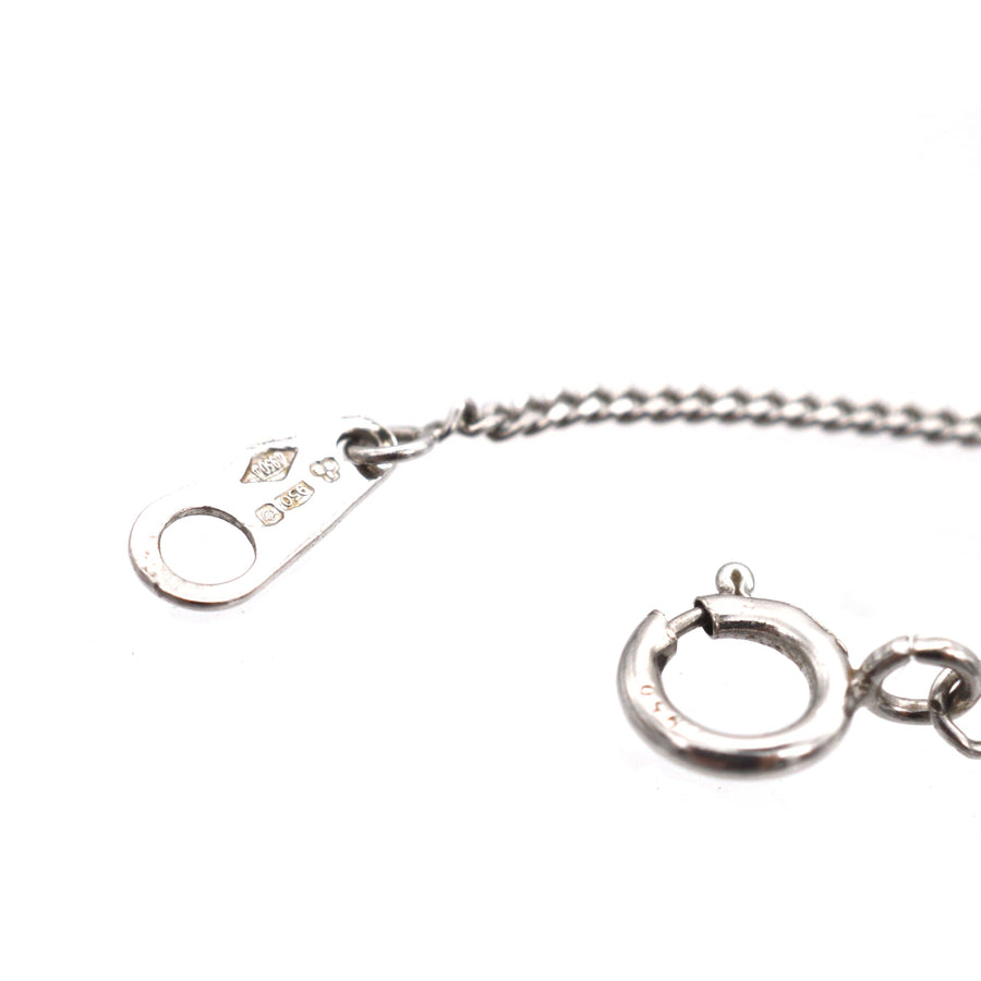 Close-up of a platinum chain clasp with a secure lobster claw and marking details.