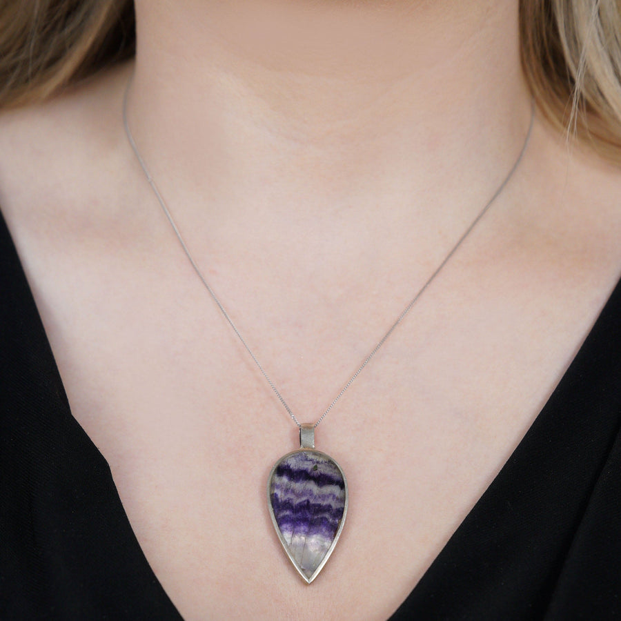 Modern silver-blue John and mother of pearl pendant displayed on a model's neck, showcasing its unique pear shape.