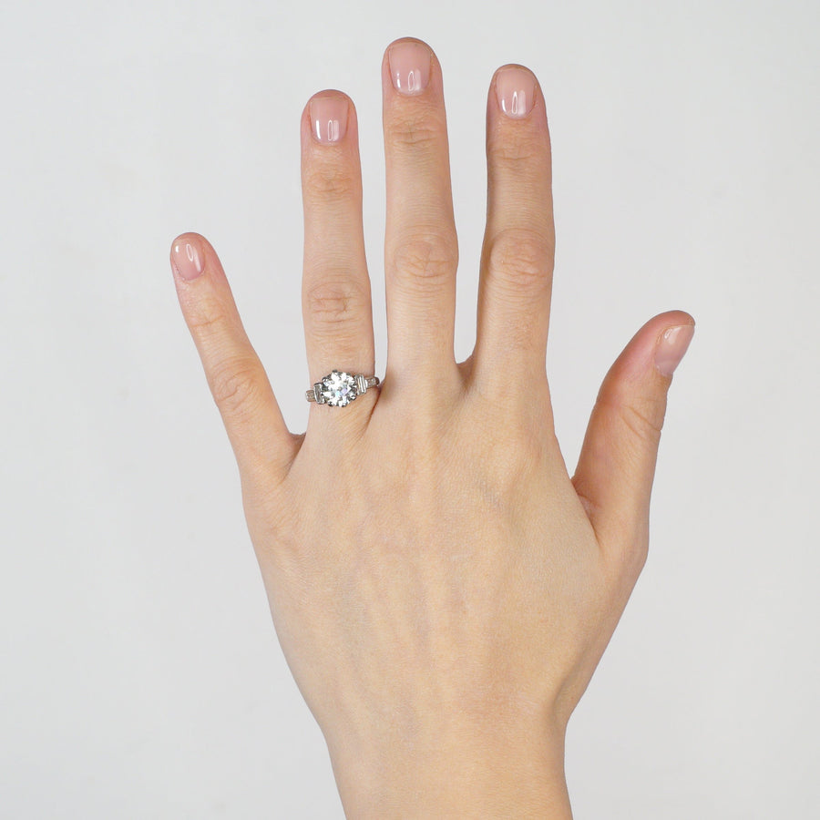 Large Art Deco platinum ring featuring 3 carat old European cut diamond and baguette diamond shoulders on a hand.