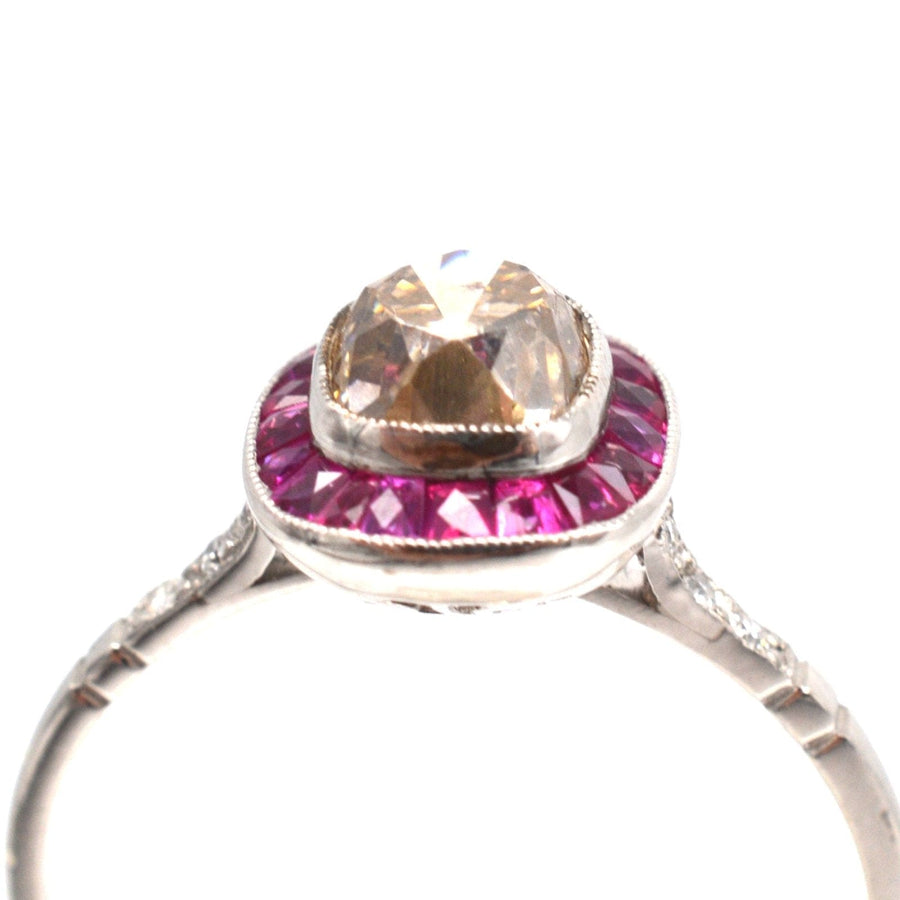 Art Deco platinum ring featuring a 1.3 carat champagne diamond surrounded by vibrant rubies.