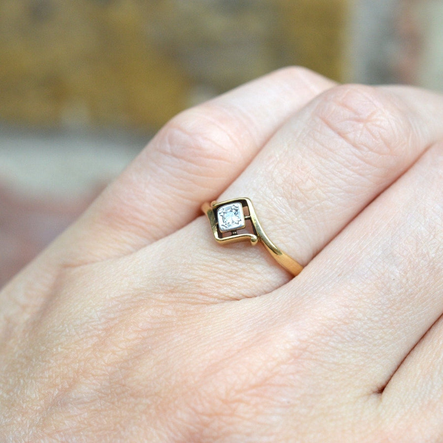 Art Deco 18ct gold diamond solitaire twist ring worn on finger, showcasing unique design and vintage elegance.