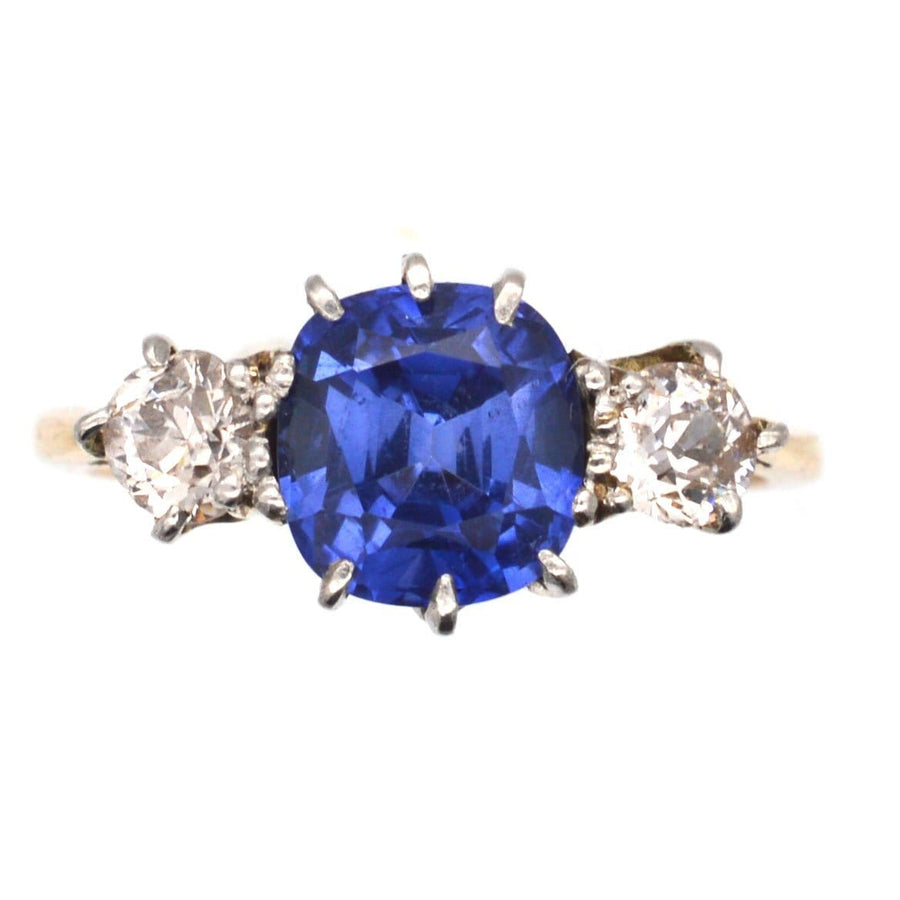 Art Deco 18ct gold and platinum three stone ring featuring a vibrant sapphire and two diamonds.