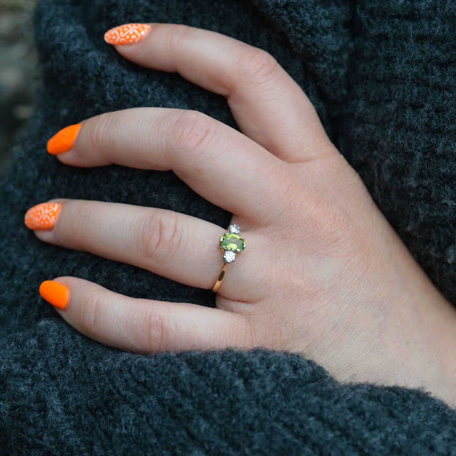 Model wearing an Art Deco 18ct gold and platinum three stone peridot and diamond ring with bright orange nails.