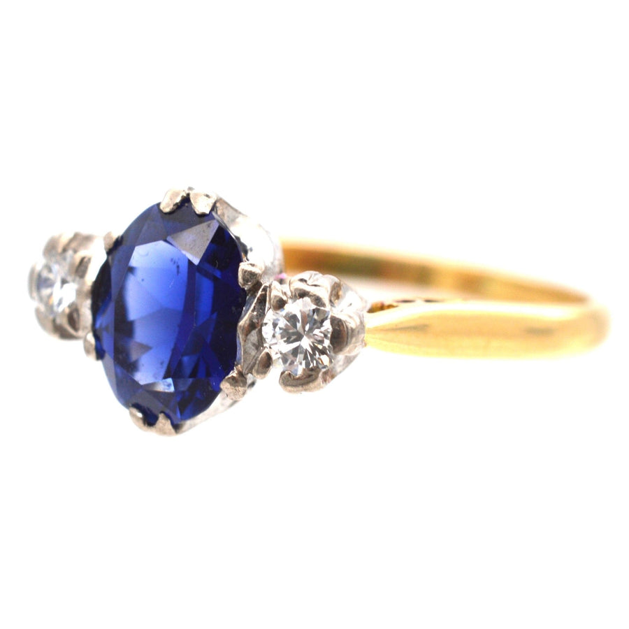 Art Deco 18ct gold sapphire and diamond three stone ring, featuring a large blue sapphire and two sparkling diamonds.