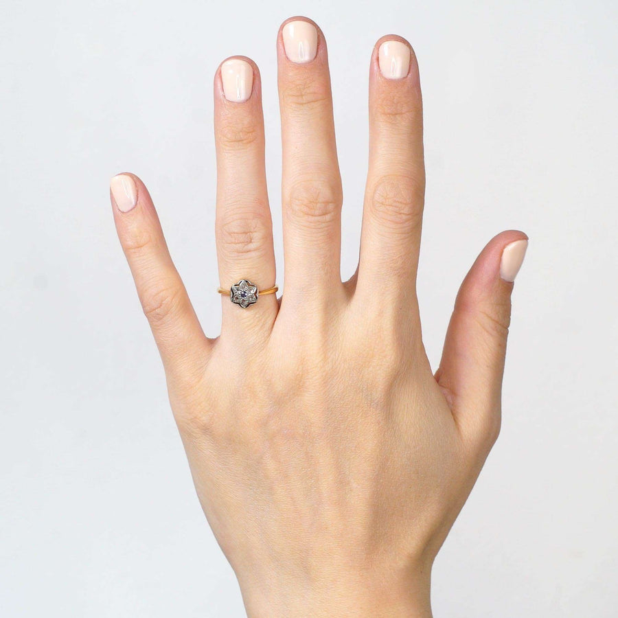 Art Deco 18ct & Platinum flower star ring with diamond and sapphire, showcased on a hand.