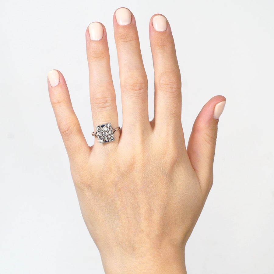 Art Deco 18ct white gold and platinum ring featuring diamonds and sapphires, showcased on a hand.
